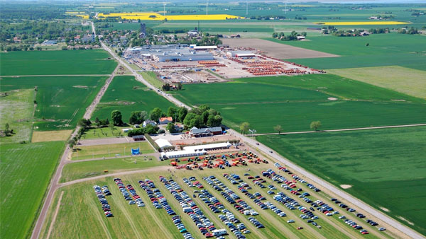 Aerial view of Väderstad, with many parked cars and agricultural machines in the field