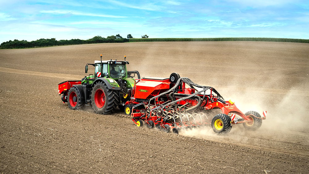 Aerial photo of a red Väderstad Proceed agricultural machine in the field.