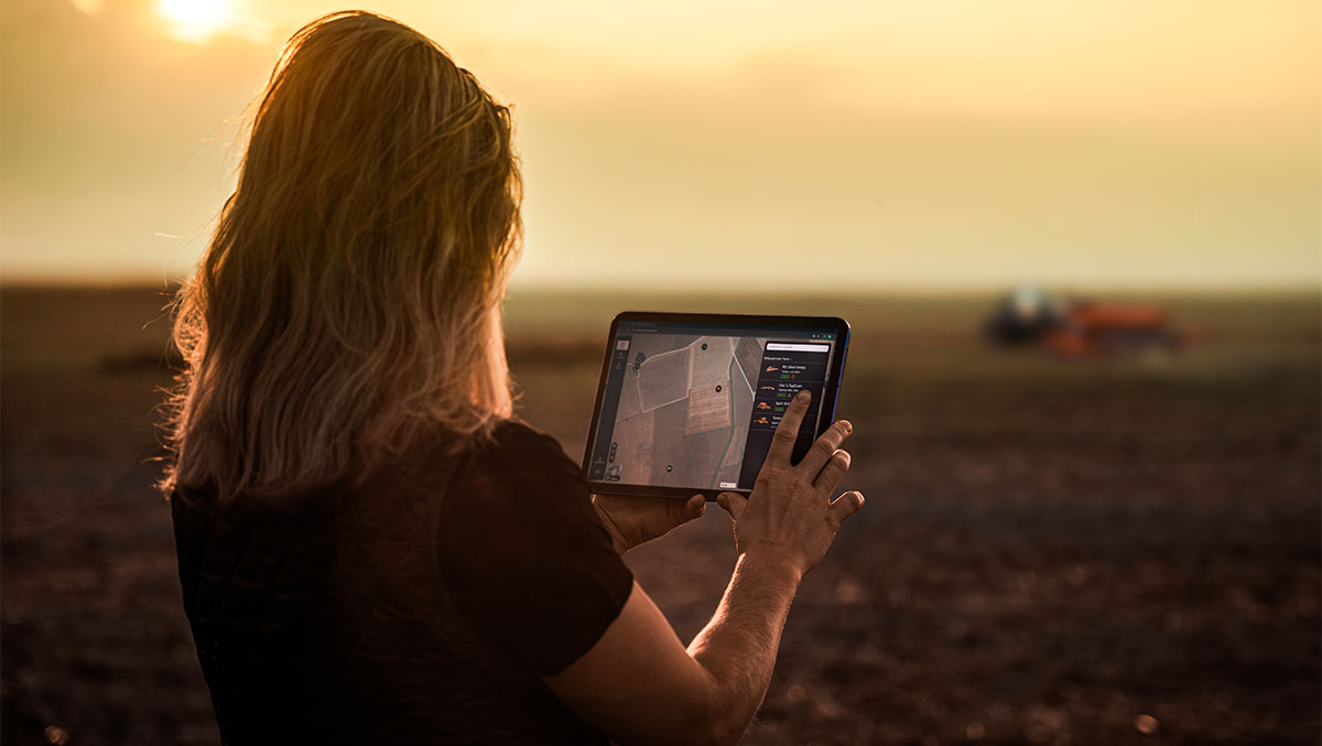 Woman standing in a field at dusk, using E-connect on her iPad