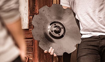 Close-up of someone holding a Väderstad cultivator disc in their hand.
